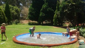 A small, round, above-ground pool surrounded by a red border, with a grassy area and trees in the background. - Perdehoek Venue (Lichtenburg)