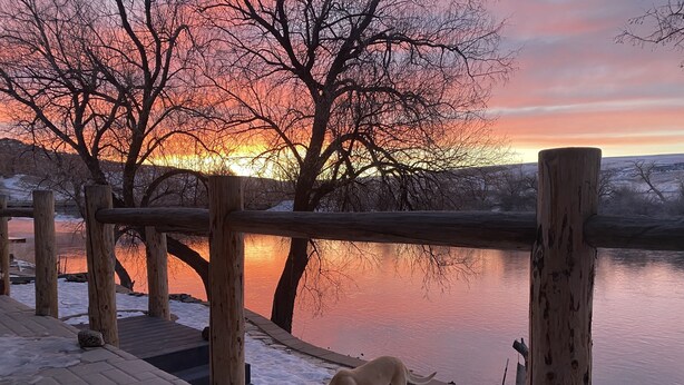 Un pontile di legno che si affaccia su un'acqua calma, con un tramonto sullo sfondo.