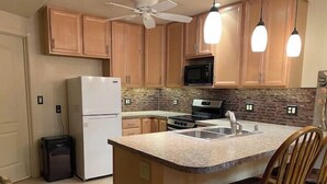 Una cucina con mobili in legno, un frigorifero, un forno a microonde, un piano cottura e un lavello.