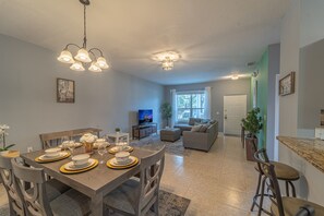 A modern living room with a dining area, a sofa set, and a television. - 3109 Amazing Villa 3 bd/2bth Close to Disney Parks (Kissimmee)