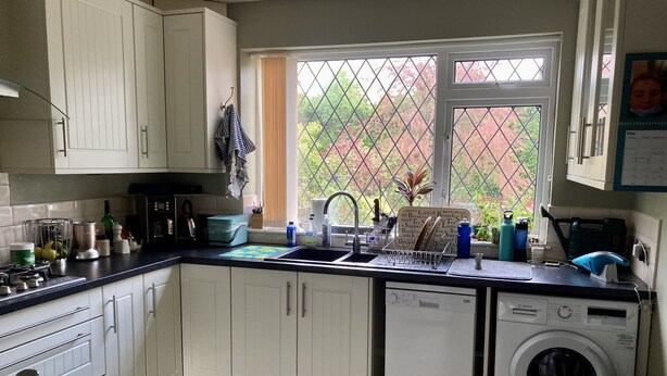 A kitchen with white cabinets, a dishwasher, a washing machine, and a window with a view of greenery. - Quiet rooms in a terraced house easy walking to shops, train (Birmingham)