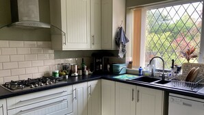 A kitchen with white cabinets, a gas stove, a sink, and a window with a view of greenery. - Quiet rooms in a terraced house easy walking to shops, train (Birmingham)