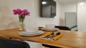 A dining table with two white bowls and a vase of pink flowers. - Hibiscus Suite - Private Studio Apartment in Rhinebeck Village (RHINEBECK)