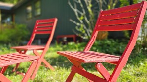 Two red chairs with a table in a grassy outdoor area. - Hibiscus Suite - Private Studio Apartment in Rhinebeck Village (RHINEBECK)