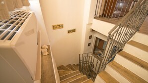 Eine Treppe mit Holzstufen und Metallgeländern, die zu einer Zwischenebene mit einer weißen Wand und einem kleinen dekorativen Gegenstand auf dem Boden führt.
