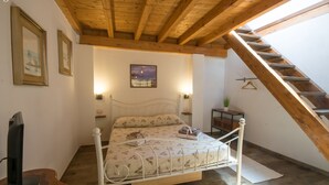 Ein Schlafzimmer mit Holzboden, einem Bett mit floralem Überwurf, einem Fernseher und einer Treppe.
