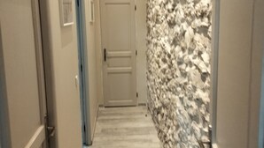 A hallway with a stone wall, a door at the end, and a staircase. - Charming gîte 300m from the picturesque village of Rougon (Rougon)