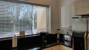 A kitchen with a window, a blender, a toaster, and a refrigerator.