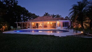 A house with a swimming pool, covered patio, and palm trees.