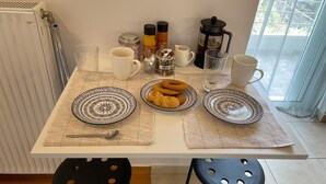 A breakfast table with plates, a coffee pot, and a sugar container.