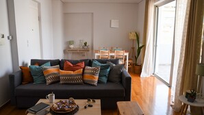 A living room with a dark sofa, a coffee table, and a dining area with a table and chairs.