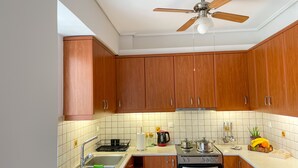 A kitchen with wooden cabinets, a stove, an oven, a sink, and a ceiling fan.