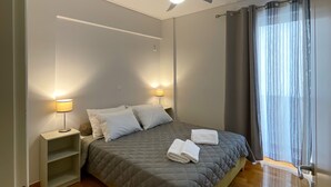 A bedroom with a bed, bedside lamps, a ceiling fan, and a window with curtains.