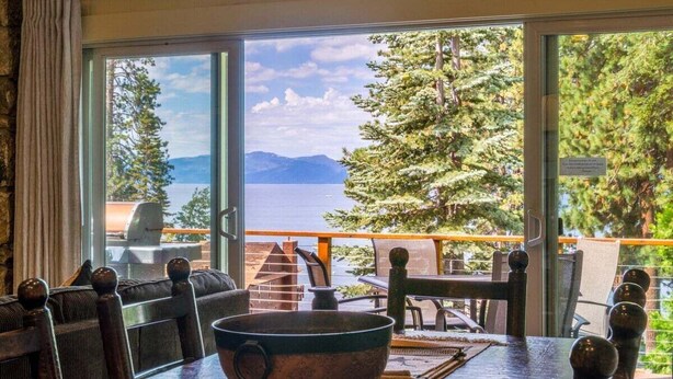 A dining area with a large table, a bowl, and a view of a lake and mountains. - Brockway Shores Condo in Kings Beach -Lakeview (Kings Beach)