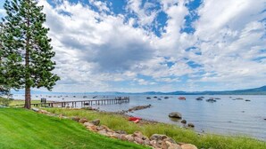 A lakeside view with a grassy area, a dock, and boats. - Brockway Shores Condo in Kings Beach -Lakeview (Kings Beach)