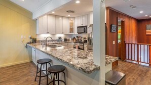 A modern kitchen with granite countertops, stainless steel appliances, and wooden accents. - Brockway Shores Condo in Kings Beach -Lakeview (Kings Beach)