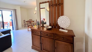 Un salon avec un meuble en bois, une table ronde et un grand miroir.