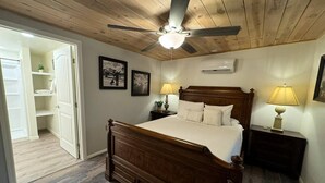 Un dormitorio con una cama de madera, un ventilador de techo y dos lámparas de noche.