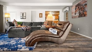 Una sala de estar moderna con un sofá seccional, un sillón de cuero y una alfombra azul estampada.