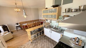Une cuisine de taille réduite, dotée de meubles en bois, d’un coin repas et d’un sol carrelé.