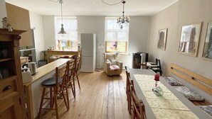 Une cuisine spacieuse avec un plancher en bois, un coin repas doté d’une longue table et un espace salon confortable.