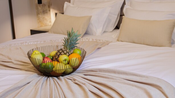 Un lit avec un panier de fruits posé dessus.