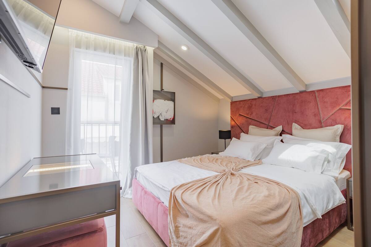 A modern bedroom with a bed, bedside table, and a window with curtains.
