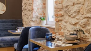 Un coin repas avec un mur en briques, une fenêtre et une table dressée avec un saladier, des verres et des couverts.