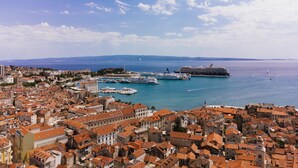 Un paysage urbain côtier avec des bâtiments historiques, une marina et un navire de croisière amarré.