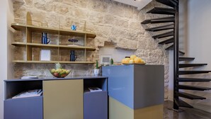 Une cuisine moderne avec un mur en pierre en arrière-plan, une bibliothèque intégrée et un escalier en colimaçon.