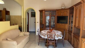 Zona pranzo con un tavolo rotondo, sedie e un mobile in legno con vetrate.
