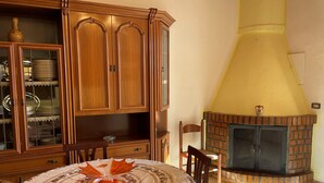 Un'area pranzo con un armadietto in legno, un tavolo con un centrotavola decorativo e un camino in mattoni.