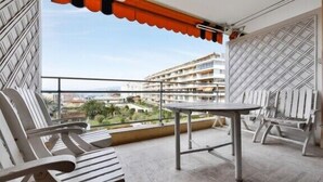 Un balcón con mesa y sillas, con vista a un paisaje urbano.