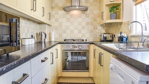 Een kleine keuken met een fornuis, oven, magnetron en een spoelbak.