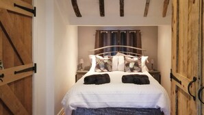Een slaapkamer met een bed, nachtkastje, lamp en een raam met gordijnen.