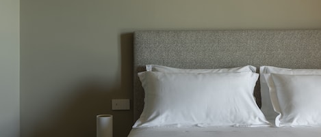 A neatly made bed with white linens and a patterned headboard.