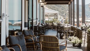 A covered outdoor seating area with wicker furniture and a view of the sea.