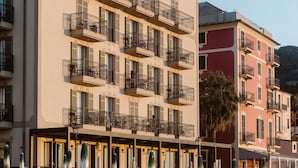 A hotel with multiple balconies, outdoor seating, and a beach view.