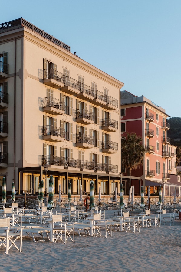 A hotel with multiple balconies, outdoor seating, and a beach view.