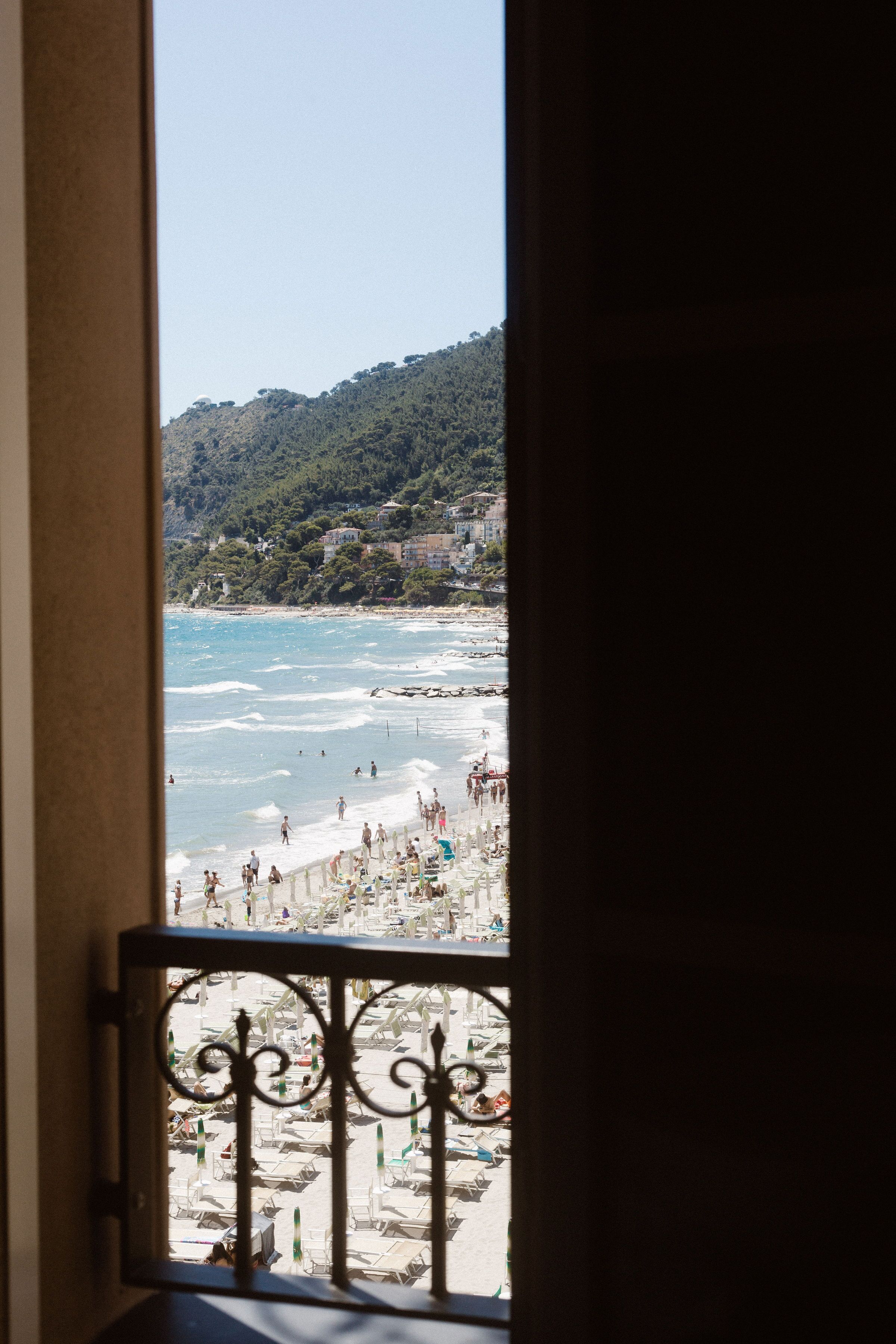 A view of a beach through a window with a metal railing.