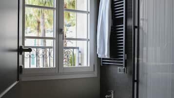Un baño moderno con ventana, dos inodoros y una toalla colgada en un perchero.