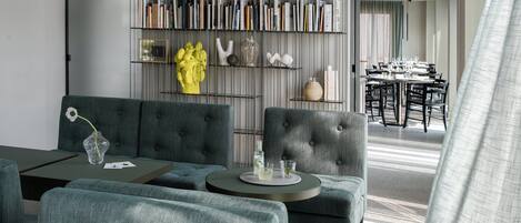Una sala de estar moderna con un sofá, una mesa de centro y una estantería llena de libros y objetos decorativos.