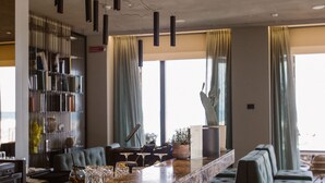 A modern bar area with a counter, stools, and a bookshelf.