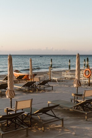 Eine Strandlounge mit Liegestühlen, Sonnenschirmen und einem Rettungsring.