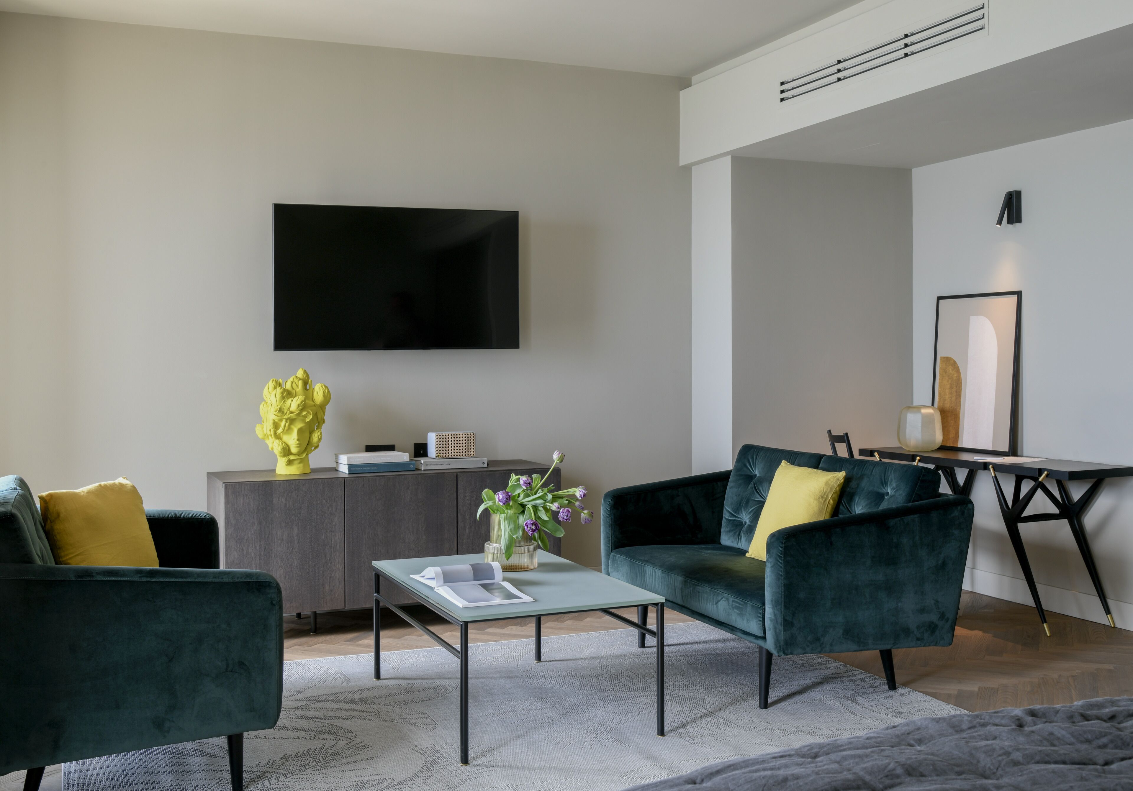 A modern living room with a sofa, coffee table, and a flat-screen TV mounted on the wall.