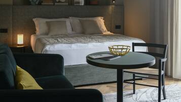A modern hotel room with a bed, bedside table, lamp, round table, and chairs.