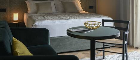 Una habitación de hotel moderna con cama, mesita de noche, lámpara, una mesa redonda y sillas.