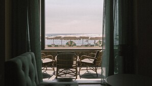 A room with a view of the sea, featuring wicker chairs and a table.