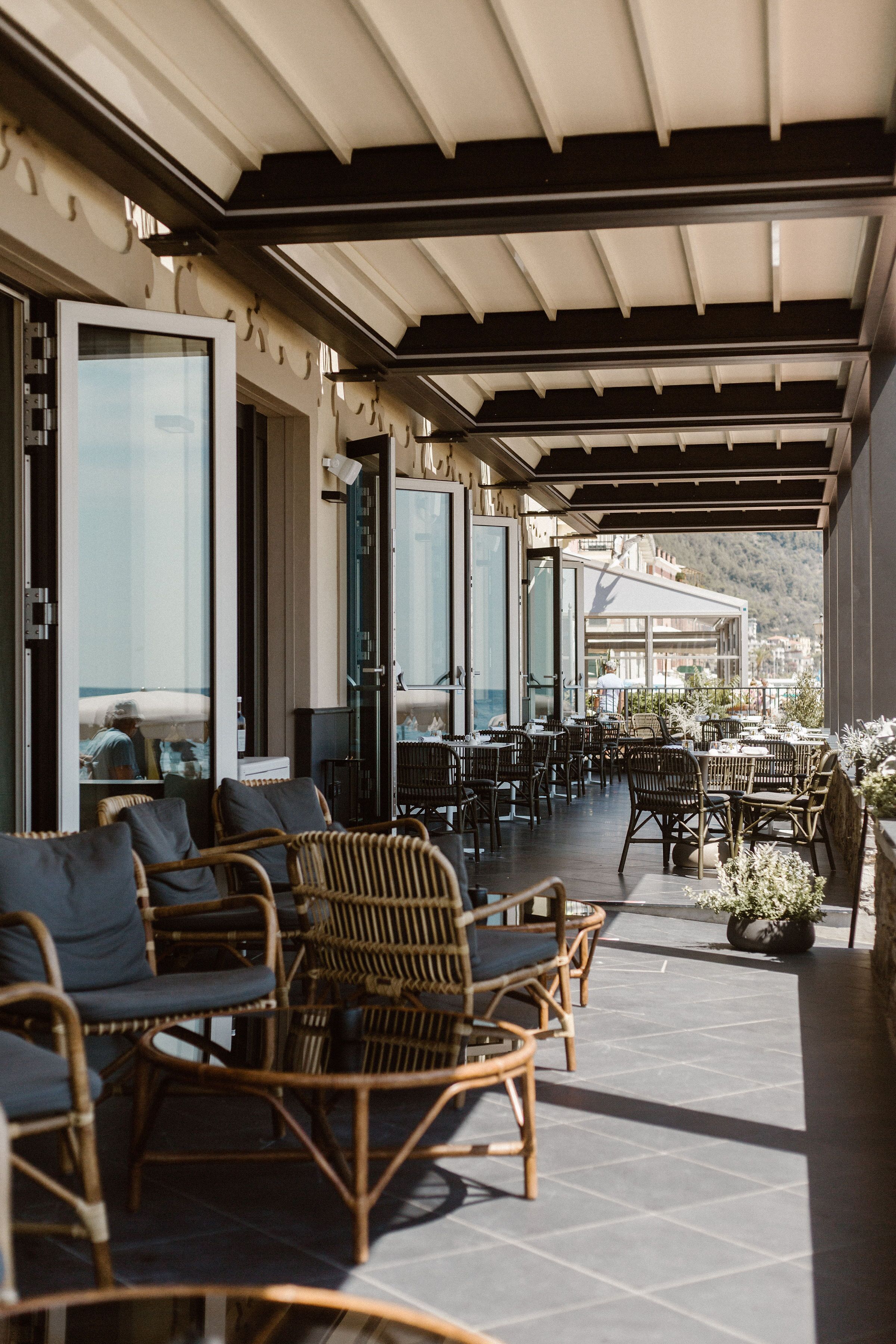 An outdoor patio area with wicker furniture, glass doors, and a view of the town.