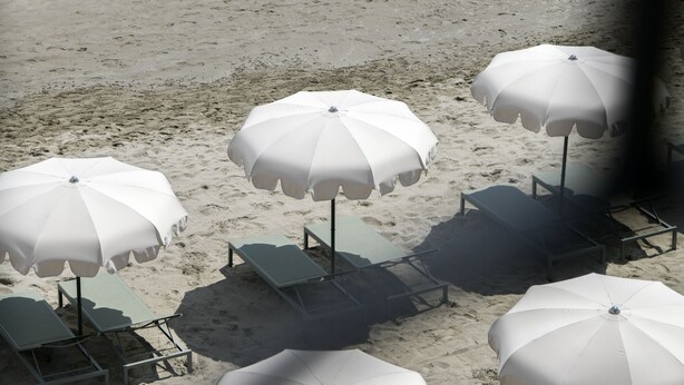A beach with white umbrellas and lounge chairs arranged on the sand.